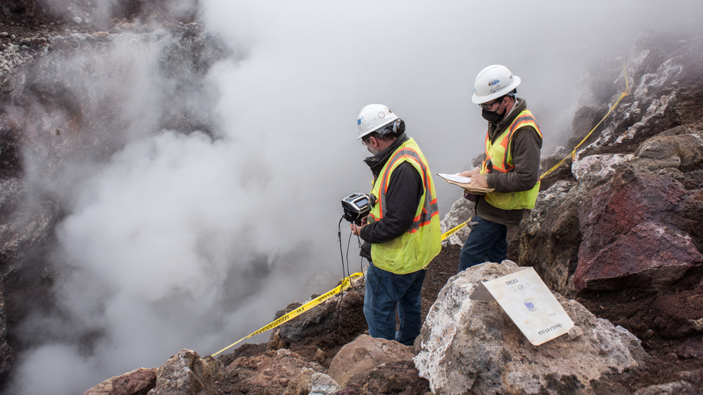 EPA inspectors in white hard hats and high-visibility vests standing at the rim of a steaming volcanic crater with air quality monitoring equipment and clipboards, yellow caution tape stretched across volcanic rock